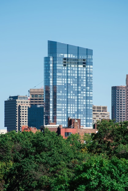 Modern skyscraper with glass facade and greenery around