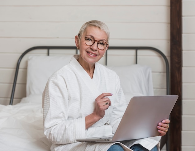 Donna senior di smiley moderno che per mezzo di un computer portatile