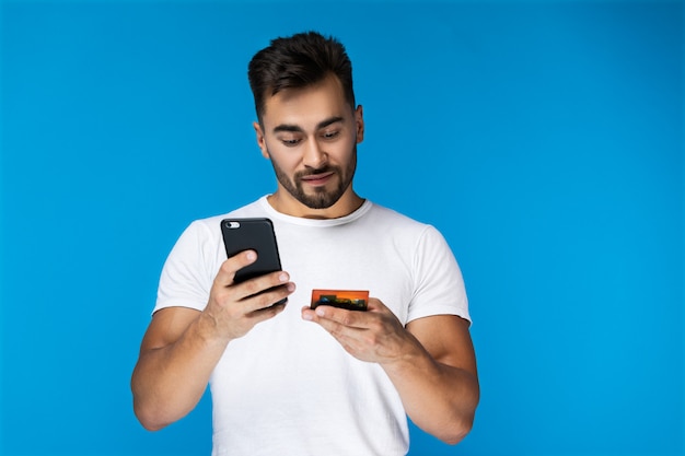 スマートな若い男が携帯電話でクレジットカードを使用して現代