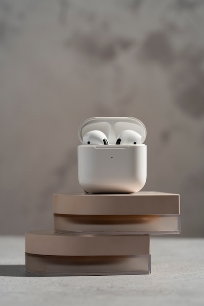 Modern wireless earphones with case displayed on round podium with soft shadows