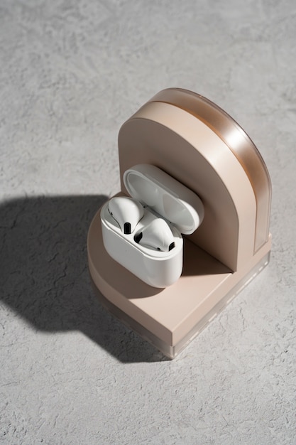 Free photo modern wireless earphones with case displayed on round podium with soft shadows