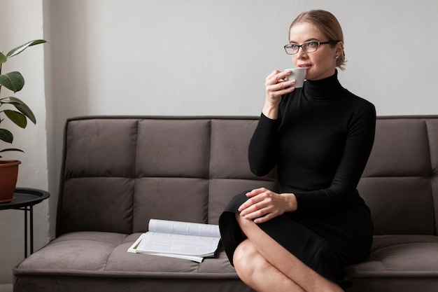 Free photo modern woman on couch drinking coffee