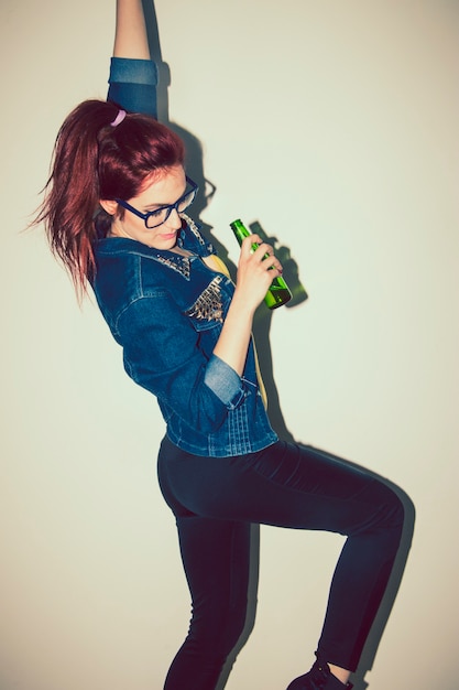 Modern woman dancing with a bottle of beer