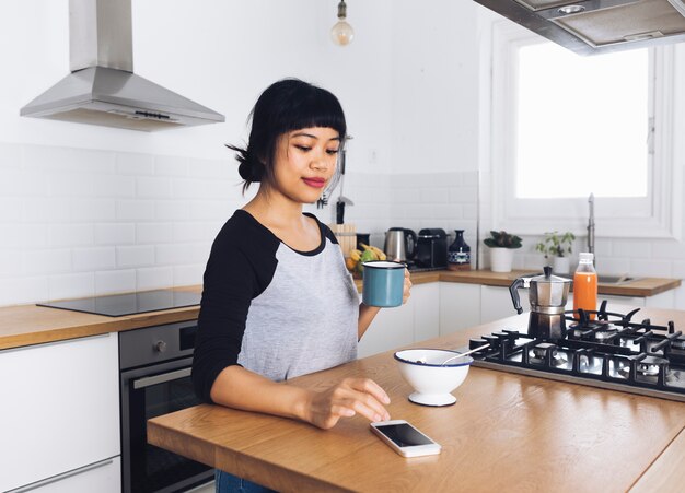 Modern woman in the kitchen using the mobile phone