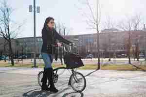 Foto gratuita bici di guida della donna moderna in città