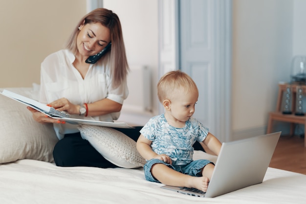 Modern woman working with child. Multi-tasking, freelance and motherhood concept