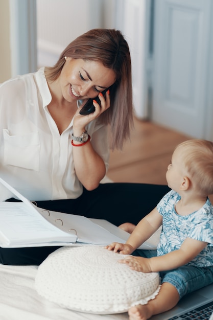 Modern woman working with child. Multi-tasking, freelance and motherhood concept