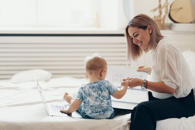 Modern woman working with child. Multi-tasking, freelance and motherhood concept