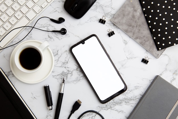 Modern workplace arrangement on marble with empty phone
