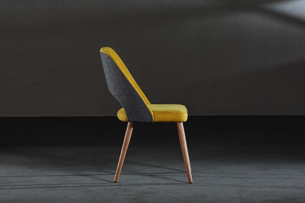 Современный желтый стул с деревянными ножками в комнате под светом