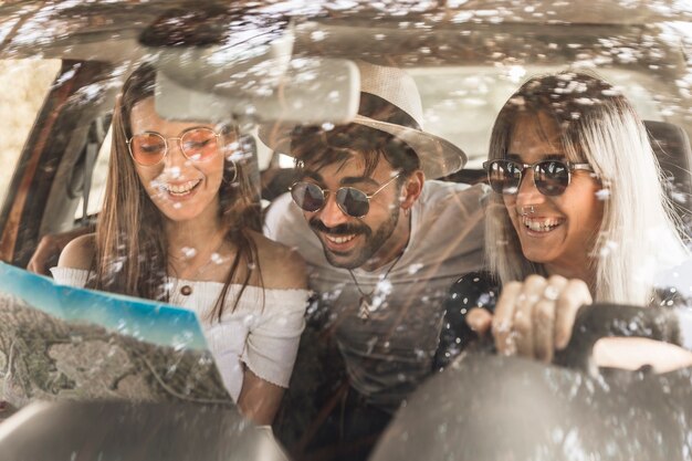 Modern young friends travelling in car looking at map