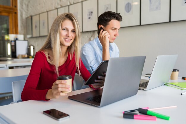 Modern young man and woman working on laptop in open space co-working office room