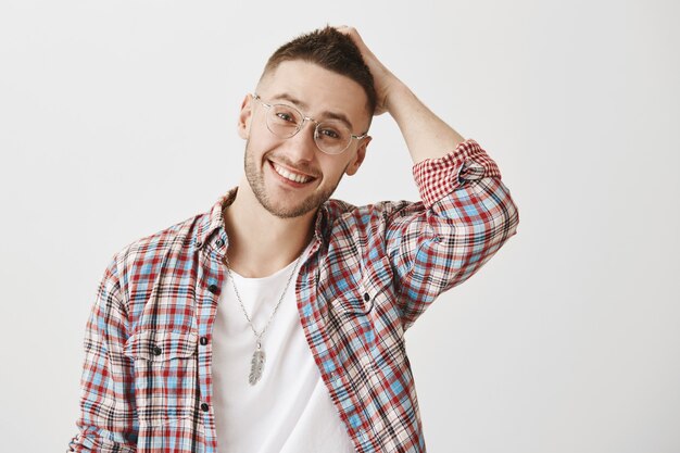 Modest handsome smiling young guy with glasses posing