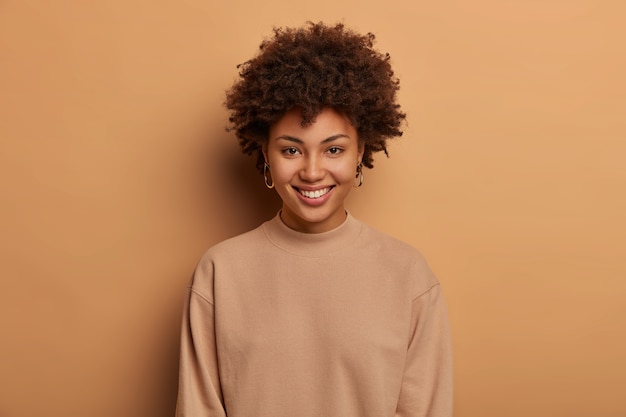 Free photo modest relaxed healthy afro american woman has tender toothy smile, enjoys lovely day, expresses positive emotions