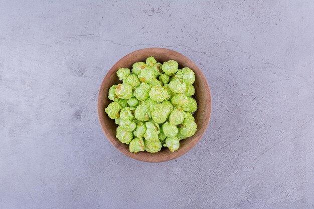 Modest wooden bowl with a heap of popcorn candy on marble background. High quality photo