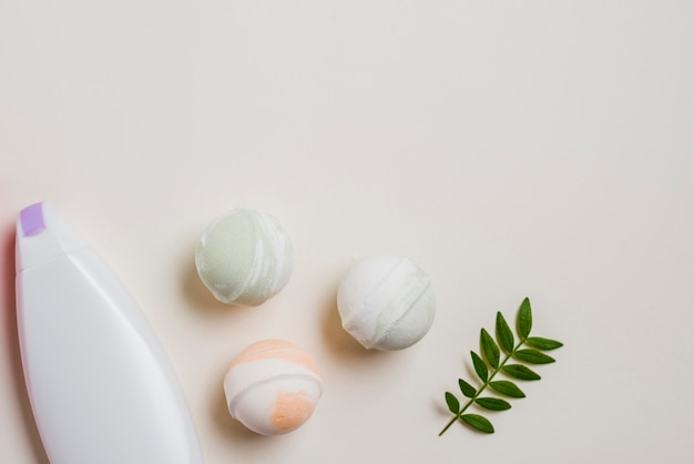 Moisturizer bottle; bath bombs and leaves on white background