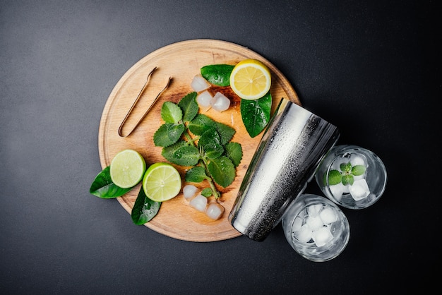 Mojito cocktail making. Mint, lime, lemon, ice ingredients and bar utensils.