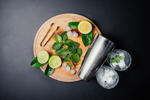 Mojito cocktail making. mint, lime, lemon, ice ingredients and bar utensils.