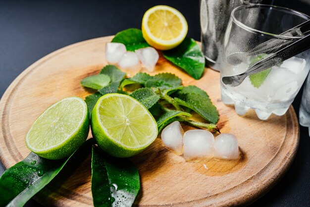 Mojito cocktail making. Mint, lime, lemon ice ingredients and bar utensils.