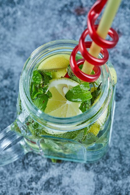 Mojito cocktail with slices of lime and mint on blue table