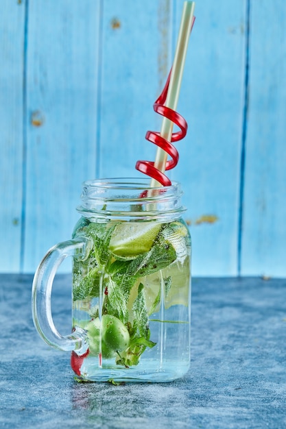 Mojito cocktail with slices of lime and mint on blue table