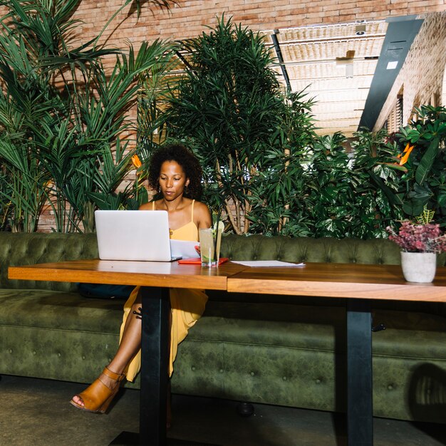 Mojito cocktail on wooden table with young woman working at laptop