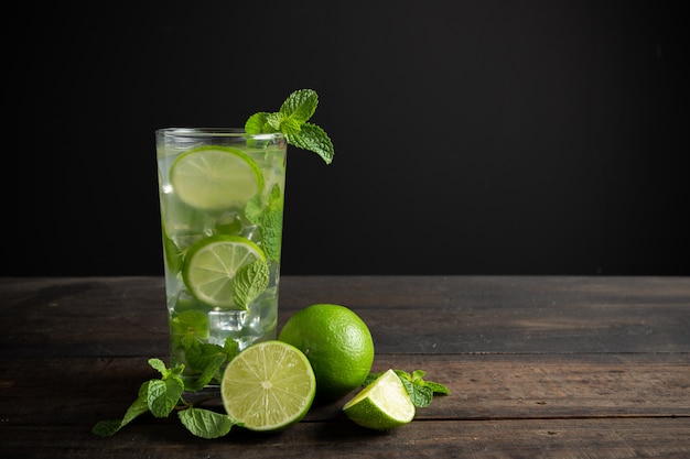 Mojito drink with lime, lemon and mint on wood table.