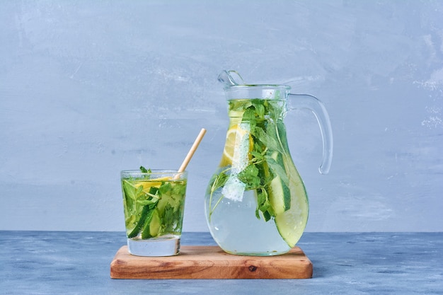 Mojito with lemon and mint on a wooden board on blue