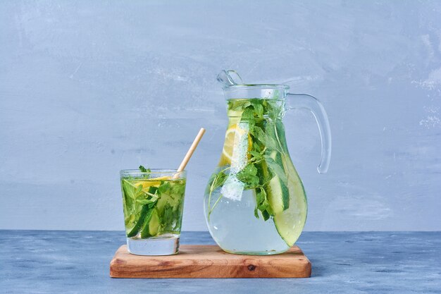 Mojito with lemon and mint on a wooden board on blue