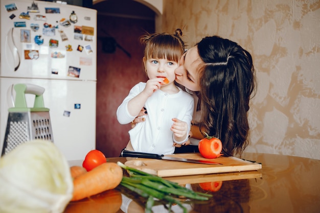 Foto gratuita la mamma insieme a sua figlia cucina le verdure a casa in cucina