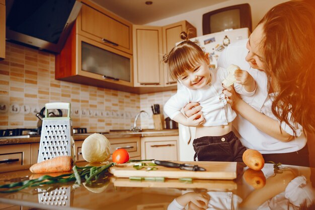 Mom along with her daughter cooks vegetables at home in the kitchen