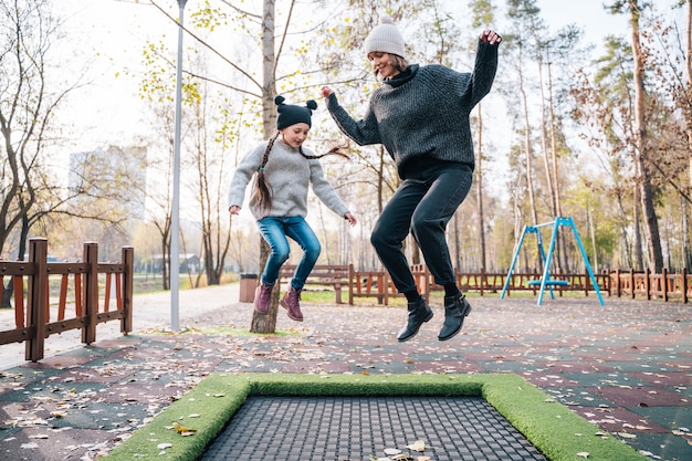 Бесплатное фото Мама и ее дочь прыгают вместе на батуте в осеннем парке