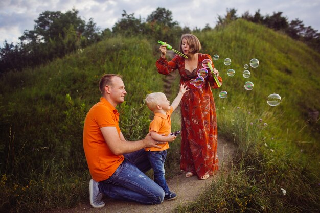 Mom and dad blow soap balloons with their son 