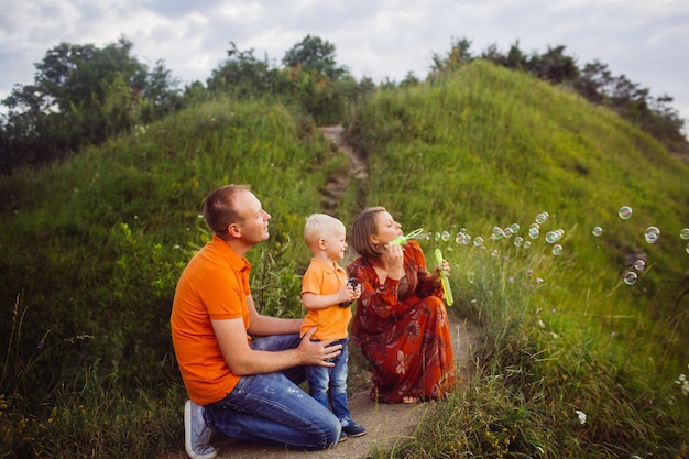 Mom and dad blow soap balloons with their son 