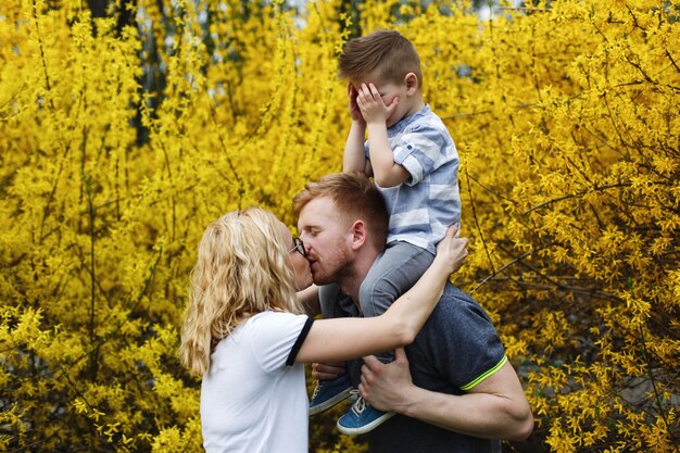 Mom and dad kiss while their little son closes his eyes