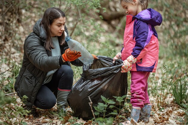 Мама и дочка очищают лес от пластика и прочего мусора.