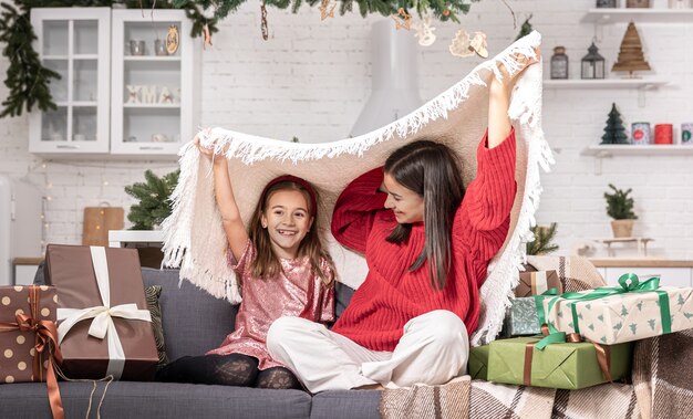 Mom and daughter on the couch in the room among the Christmas gifts.