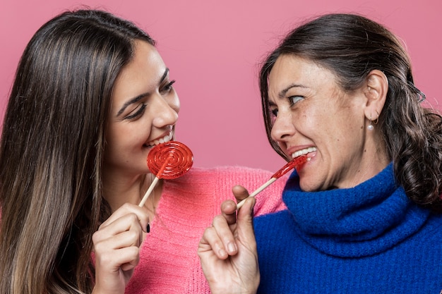 Free photo mom and daughter eating lollipops