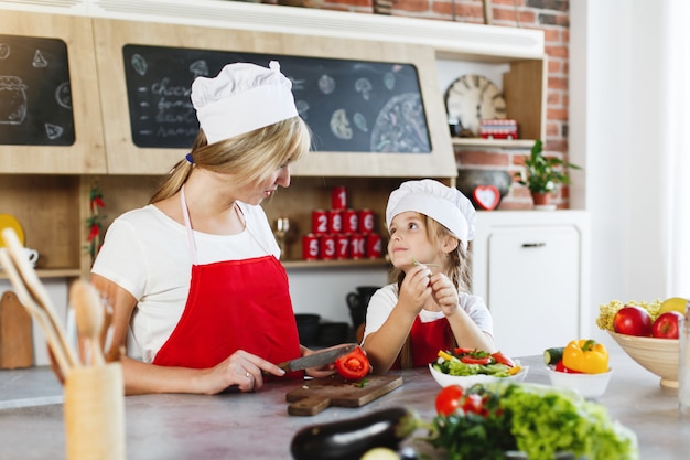 Mom and daughter have fun on the kitchen cooking different vegetables for a dinner