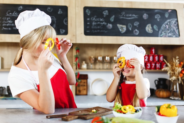 Mom and daughter have fun on the kitchen cooking different vegetables for a dinner