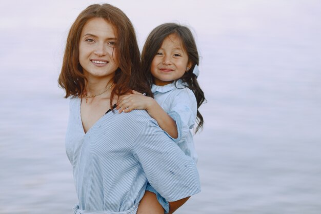 Mamma e figlia in abiti identici. famiglia che gioca in riva al fiume.