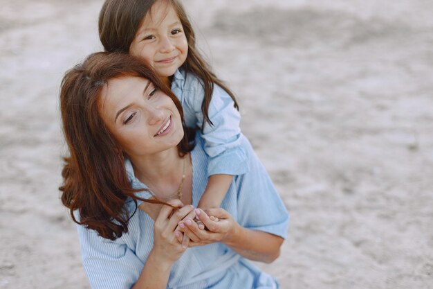 Mom and daughter in identical dresses. Family playing by the river.