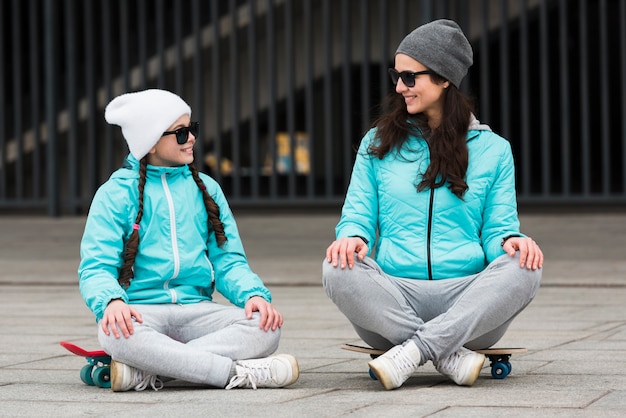 Free photo mom and daughter sitting on skateboard