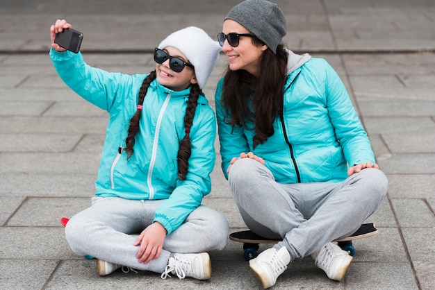 Mamma e figlia su skateboard prendendo selfie