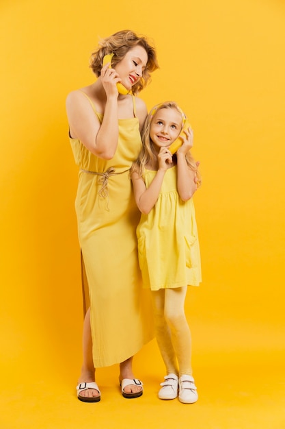 Мама и дочь, используя бананы в качестве телефона