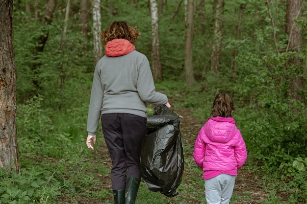 ゴミ袋を持ったママと娘がゴミから環境をきれいにします。