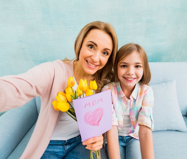 Mom and daughter with present smiling taking photo