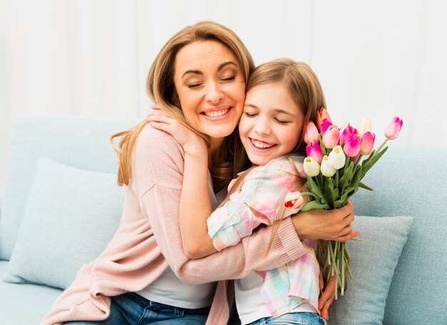 Mom and daughter with satisfied face hugging each other