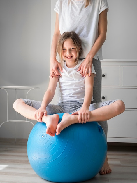 Mom and girl exercise on ball together