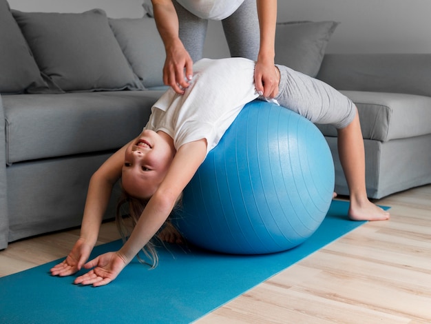 Free photo mom help girl to exercise on ball